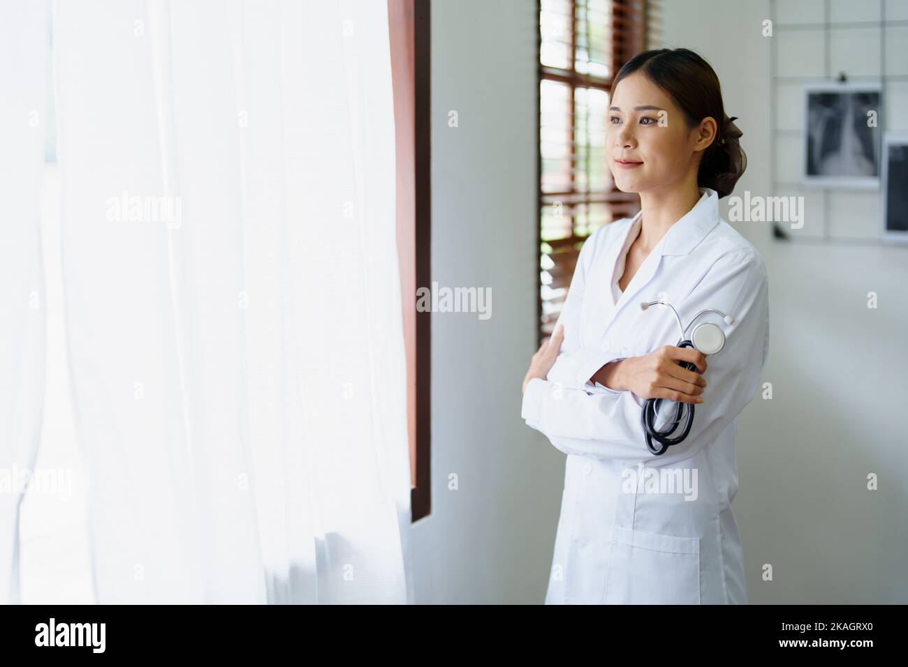 Porträt einer asiatischen Ärztin, die nach einer Arbeitspause glücklich lächelt und ein Stethoskop hält Stockfoto