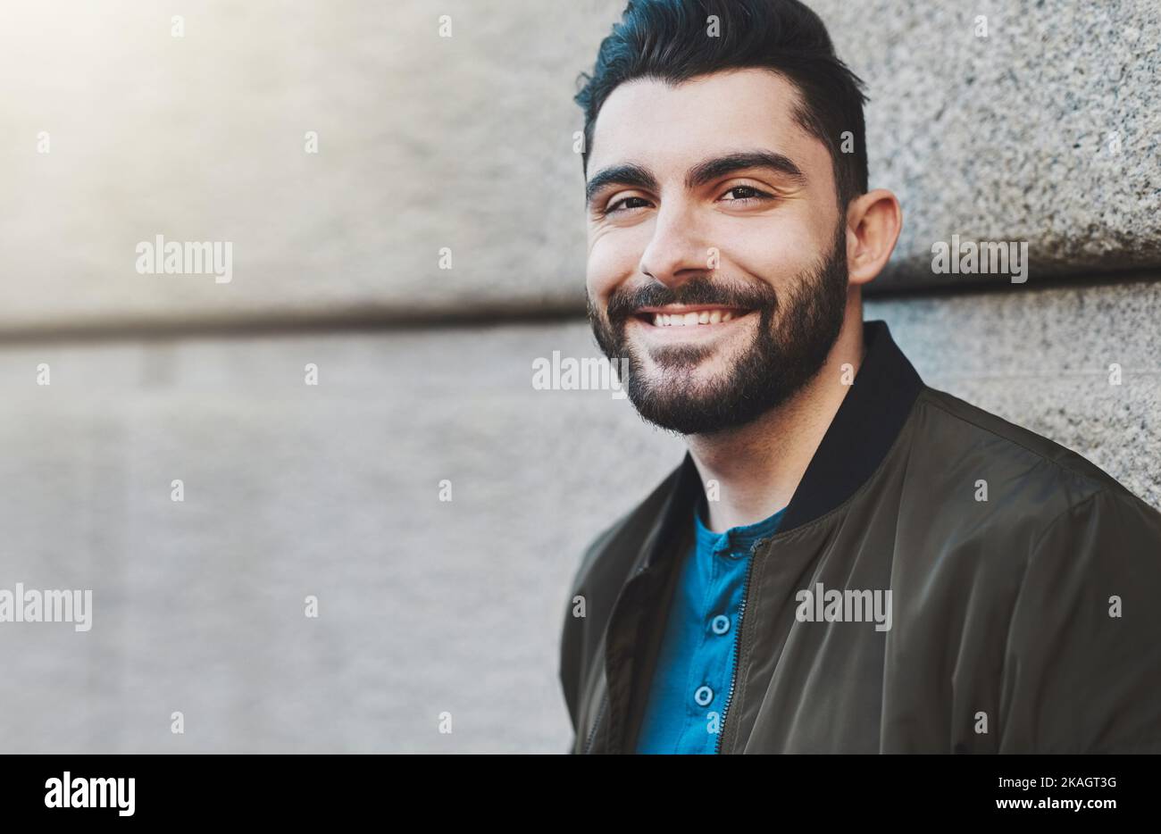 Ich liebe es, draußen zu sein. Ein hübscher junger Mann, der draußen in der Stadt gegen eine Wand steht. Stockfoto