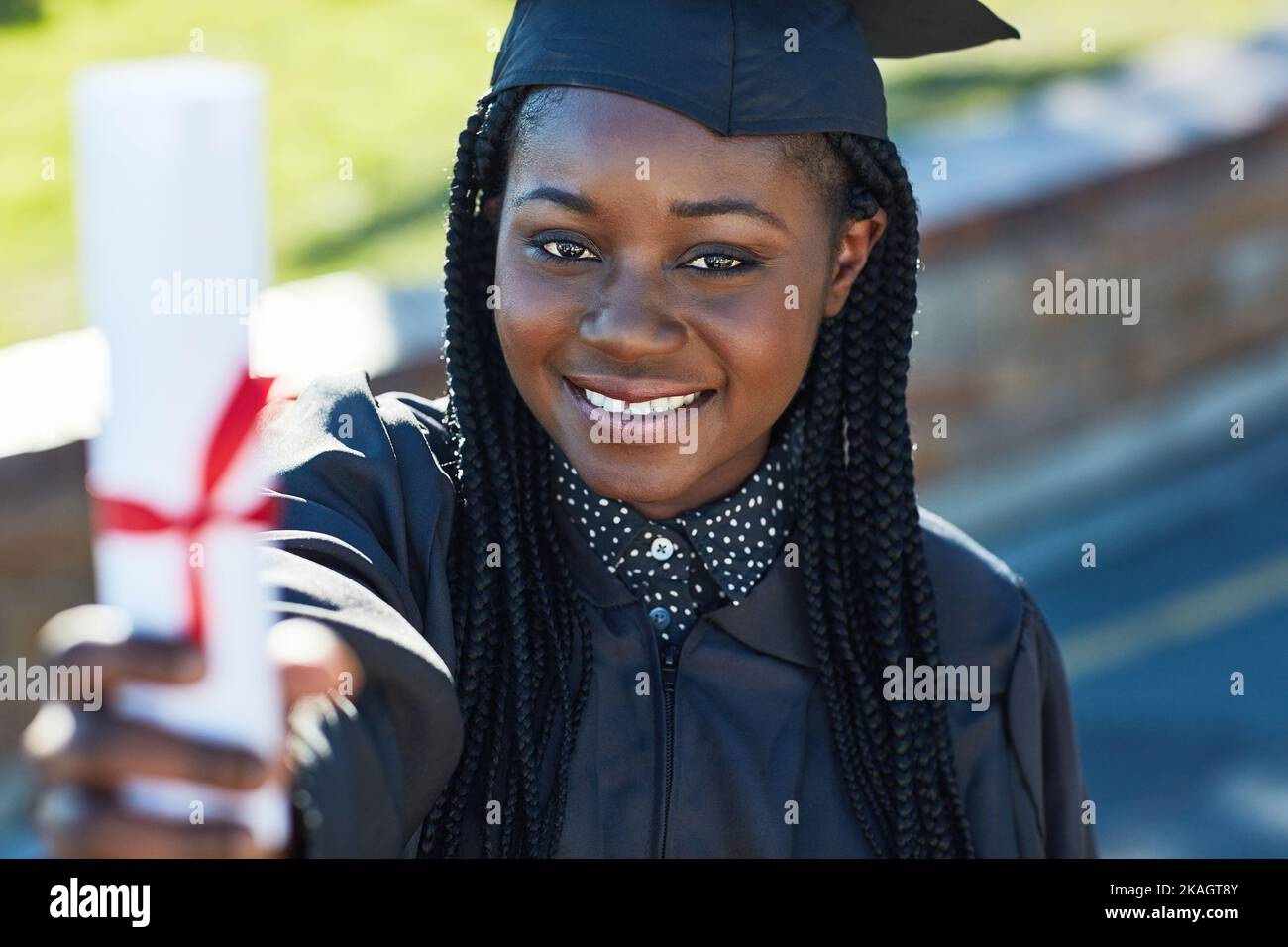 Raten Sie mal, wer gerade seinen Abschluss gemacht hat. Porträt einer jungen Studentin, die am Abschlusstag ihr Diplom hält. Stockfoto