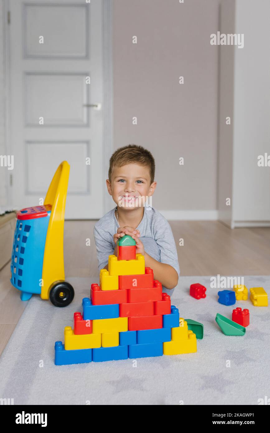 Junge spielt im Kindergarten mit Bausteinen. Das Kind spielt zu Hause mit bunten Spielzeugblöcken Stockfoto