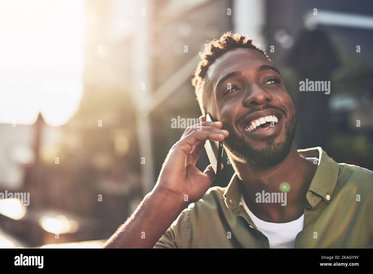 Es ist so schön, Ihre Stimme zu hören. Ein junger Mann benutzt sein Handy, während er draußen steht. Stockfoto