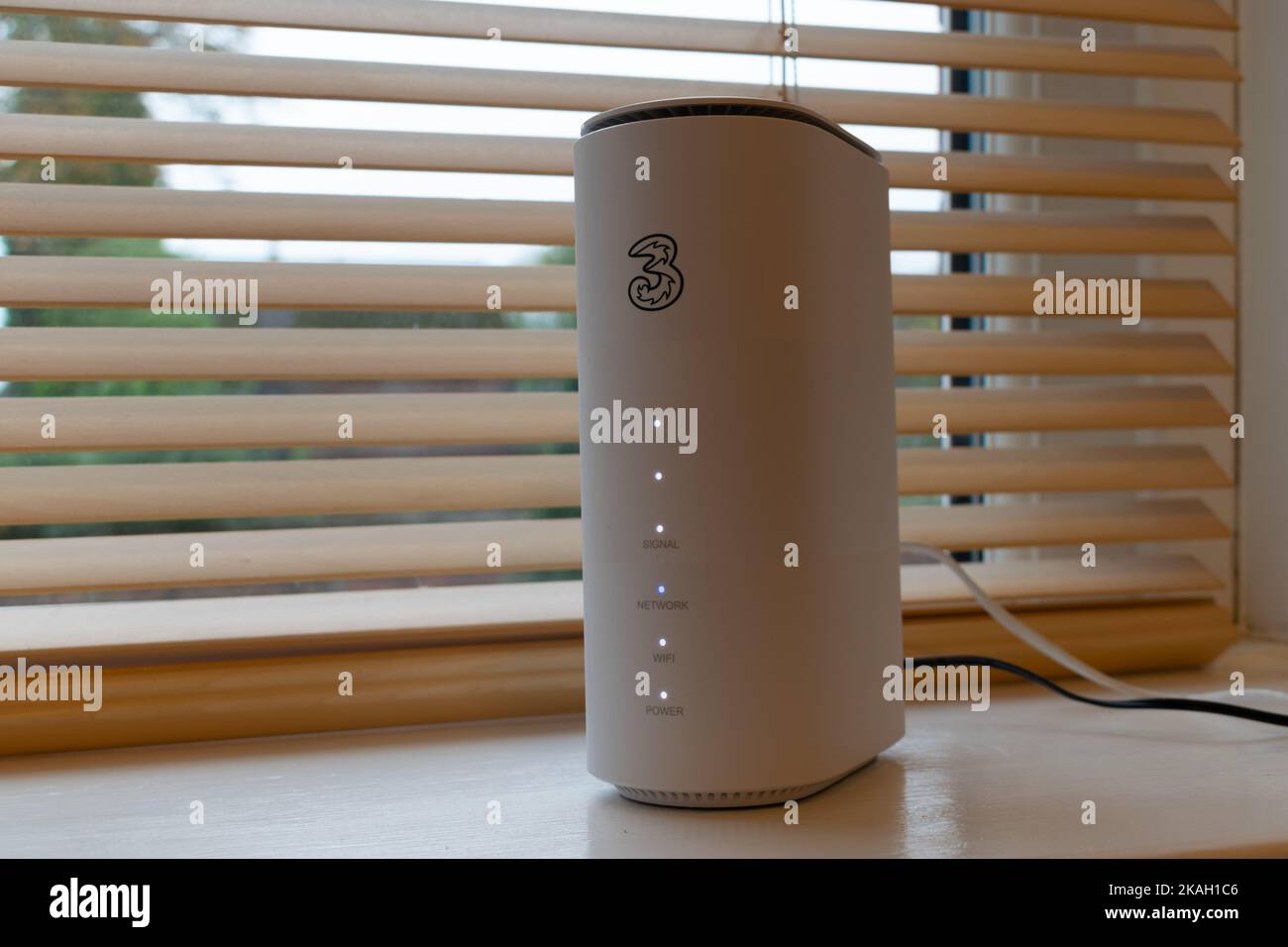 5G Router-Position im Fenster unten mit Holzjalousien dahinter. Drei 3-Netzwerk, Großbritannien Stockfoto