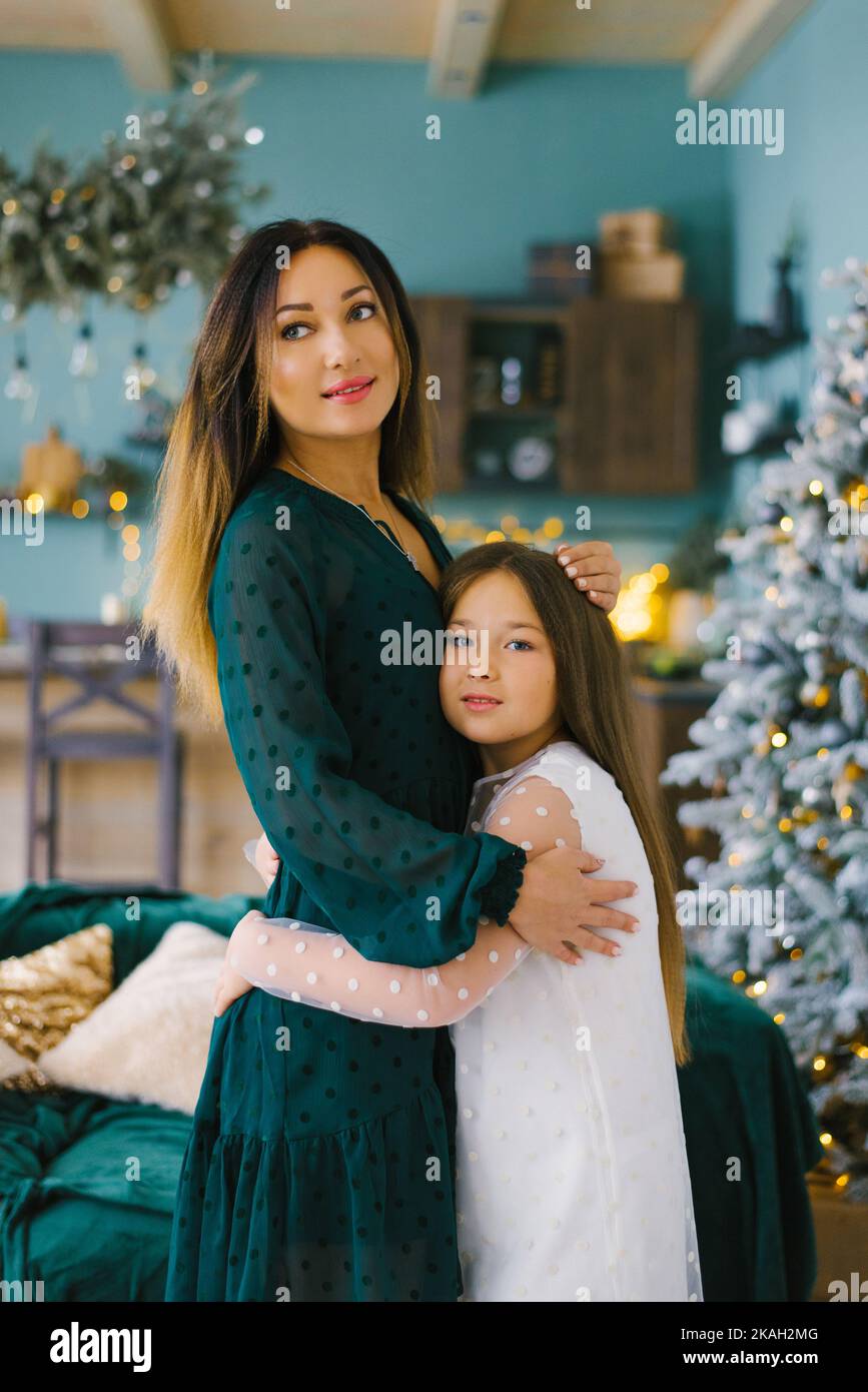 Mutter und Tochter umarmen sich vor dem Hintergrund der Weihnachtsdekoration im Wohnzimmer Stockfoto