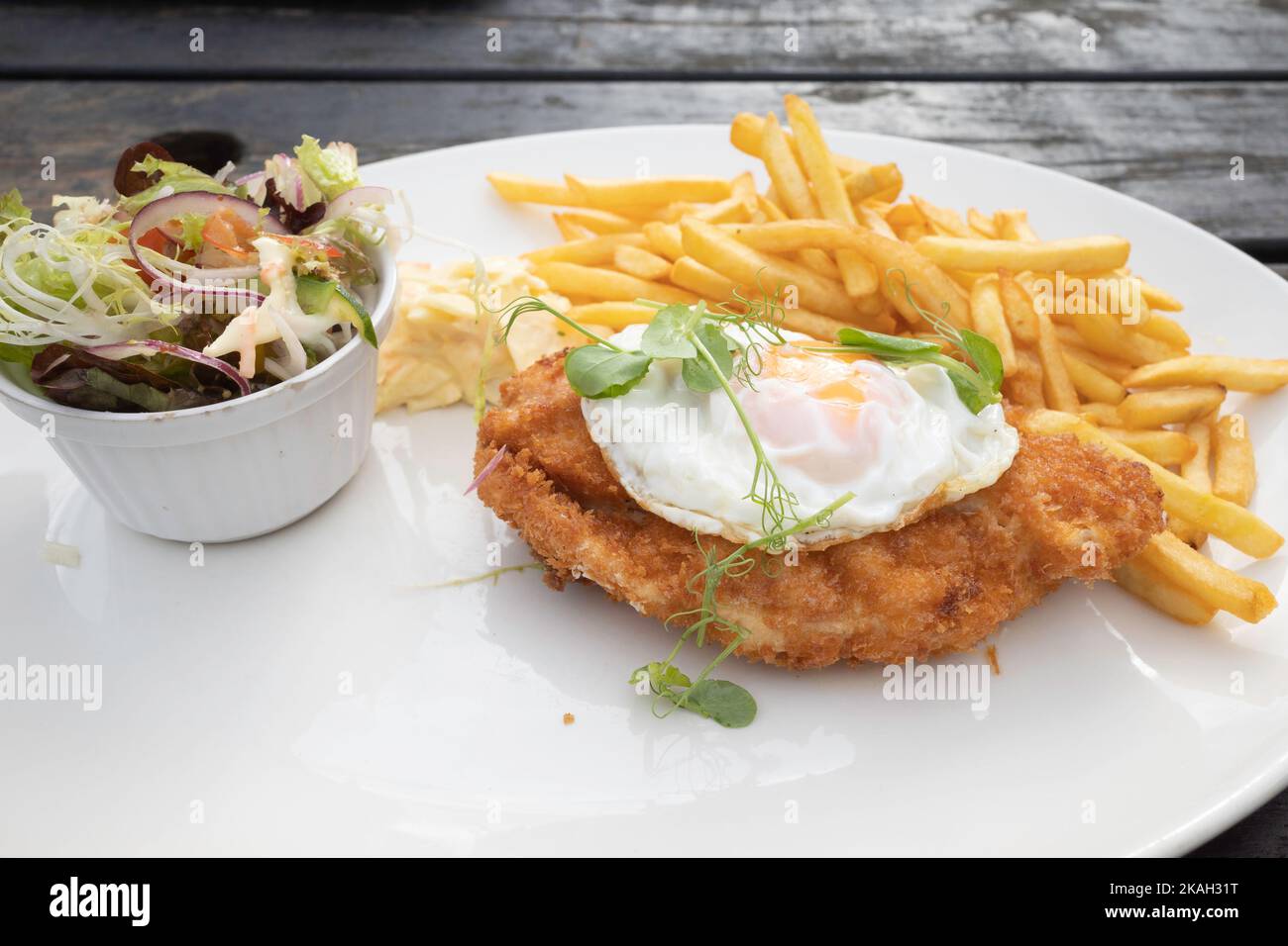 Lord Stones Café Mittagessen Huhn Mailanese mit Pommes frites coleslaw und mischt Blätter Salat mit einem Spiegelei auf der Oberseite Stockfoto