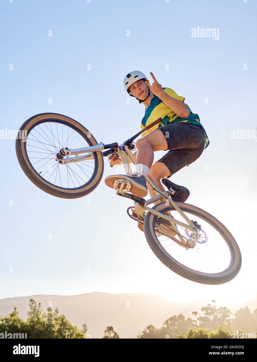 Fahrrad, springen und Felsen an der Hand Schild mit einem Mann bmx Fahrer springen über eine Rampe auf einem Trail oder Kurs in der Natur. Himmel, Berg und Radfahren mit einem Männchen Stockfoto