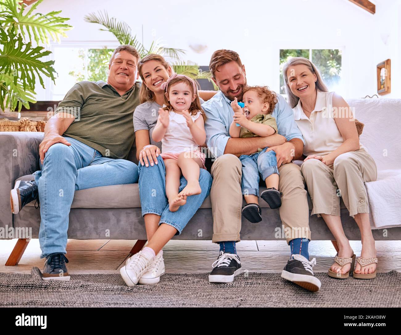 Kinder, Eltern und glückliche Großeltern auf dem Sofa, Generationen der Familie zusammen im Wohnzimmer. Liebe, Haus und Paar mit Kindern, Oma und Opa Stockfoto