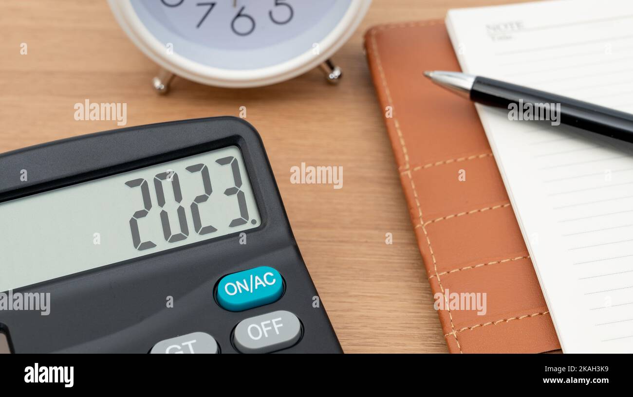 Elektronischer Taschenrechner mit 2023 im Hintergrund mit Uhr und Tagebuch. Geschäftskonzept für das neue Jahr. Stockfoto