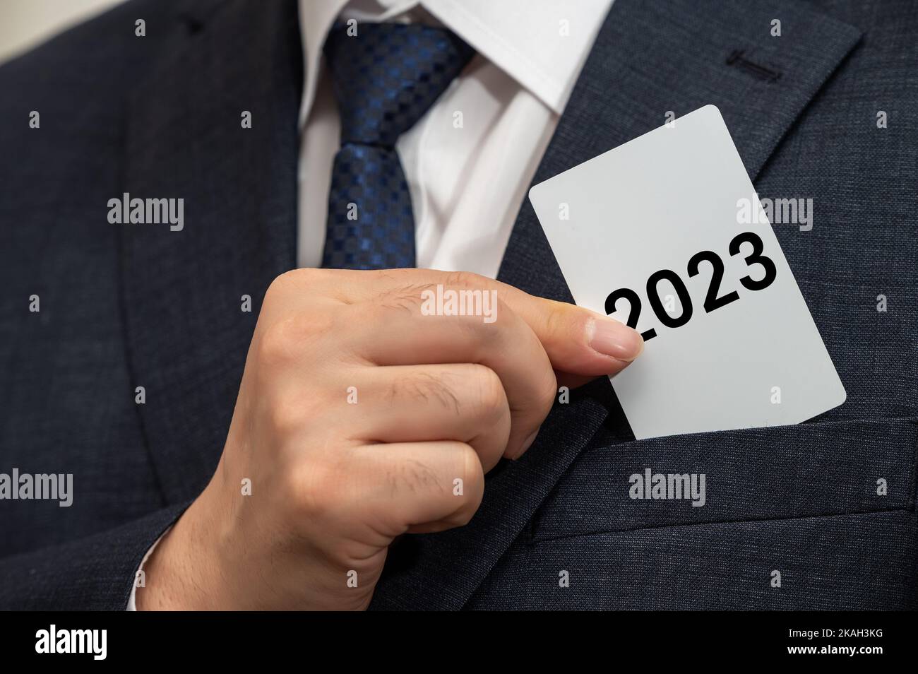 Ein Geschäftsmann hält in der Hand eine weiße Karte mit 2023 darauf. Geschäftszielkonzept für das neue Jahr. Stockfoto