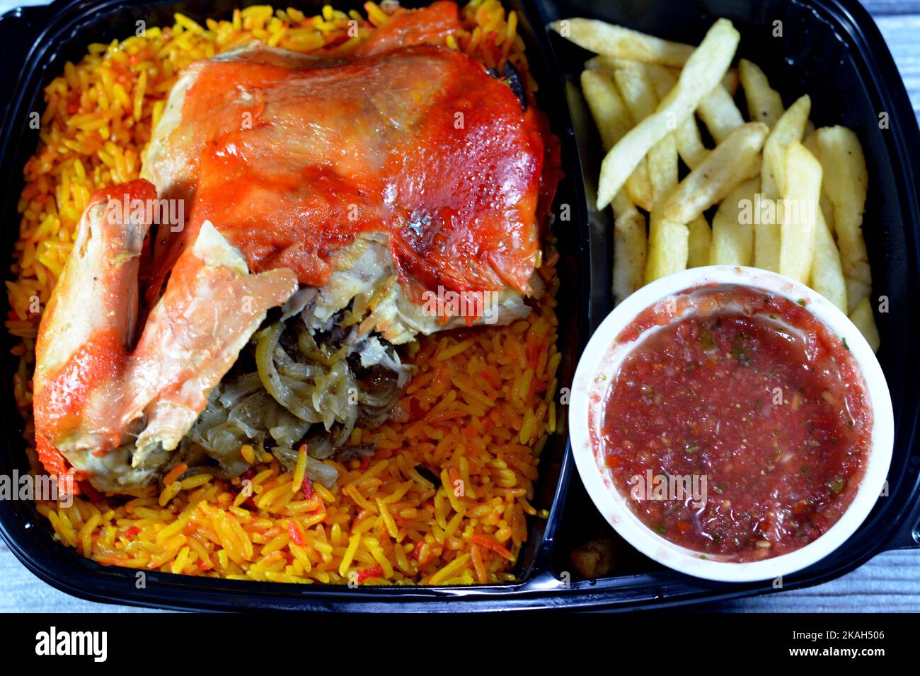 Huhn-Mandi mit langem Basmati-Reis und pommes frites, serviert mit Tomaten-Dakos-Sauce, selektive Fokus des Jemen Rezept von Mandi-Huhn mit Gewürzen und Stockfoto
