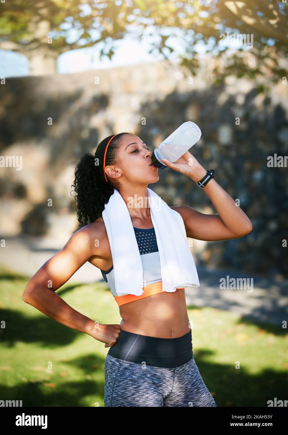 Eine sportliche junge Frau trinkt Wasser während des Trainings im Freien. Stockfoto