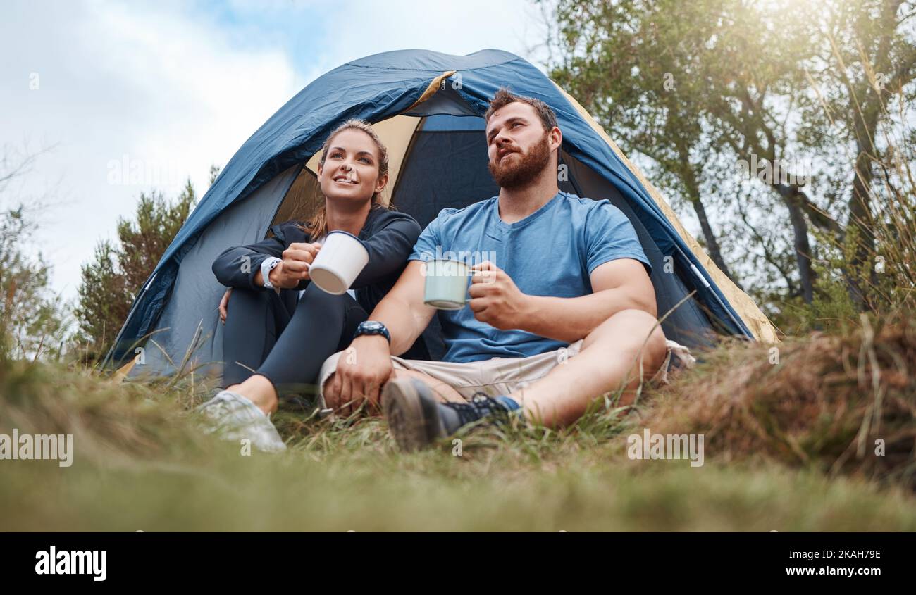 Camping, Zelt und Natur zu zweit mit Kaffee, Tee oder heißer Schokolade Entspannen Sie sich im Wald oder im Wald. Grasfeld Bäume, Morgen Blick und Camper Menschen Stockfoto
