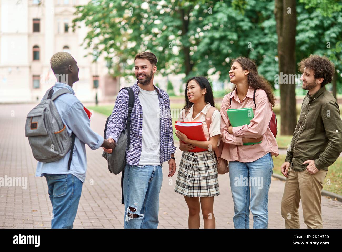 Eine Gruppe von Studenten trifft einen neuen Freund mit einem Handschlag. Stockfoto