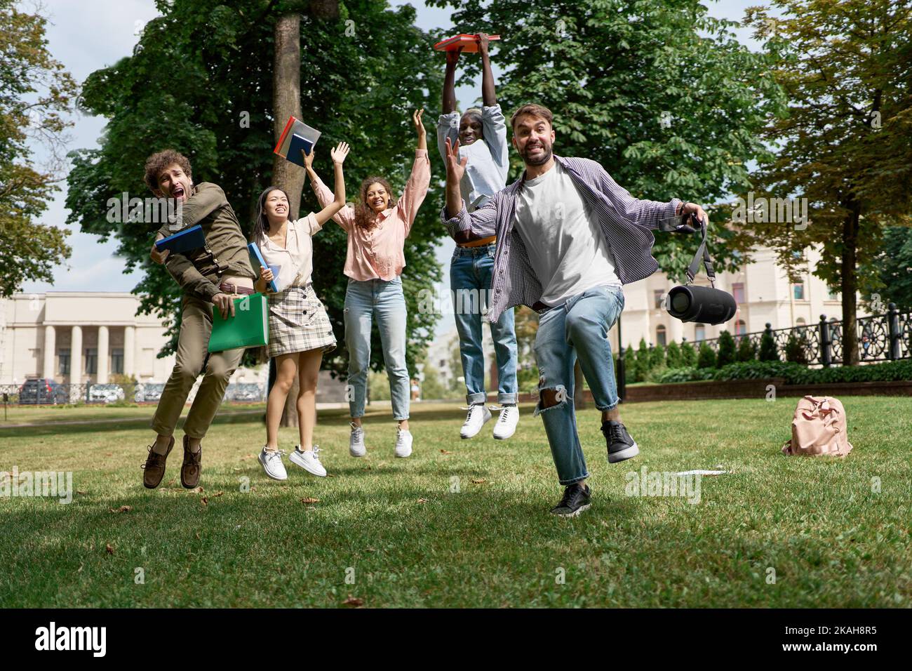 Gruppe von fröhlichen Studenten im Stehen auf dem Gras im Park. Stockfoto