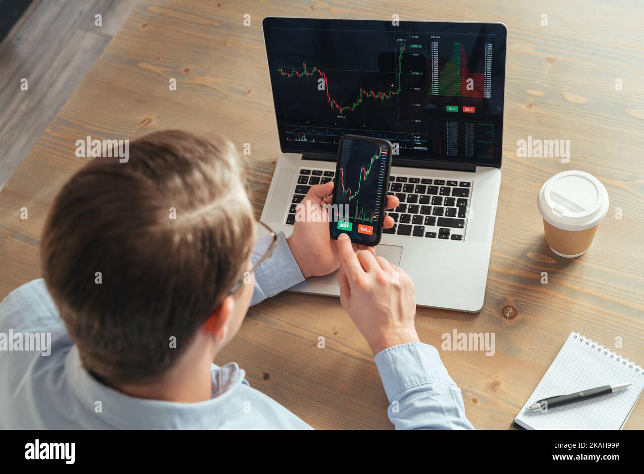 Über der Schulter Draufsicht des Business man Trader Investors mit Smartphone Kryptowährungs-App Finanzmarktanalyse, Trading-Daten Index Chart mit Kauf- und Sell-Buttons Stockfoto