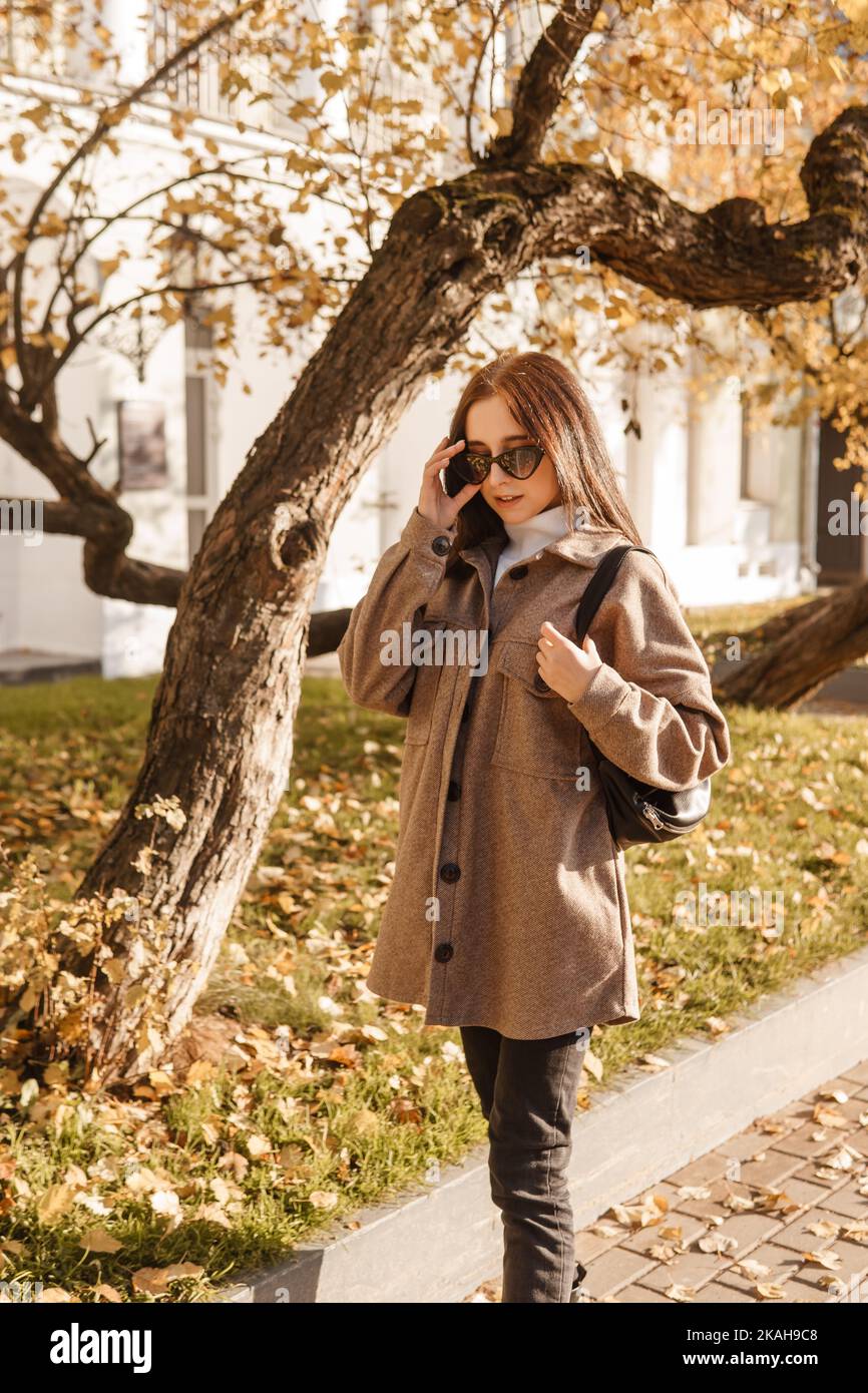 Eine stilvolle Brünette Frau geht durch die Herbststadt. Die Jahreszeit ist der Herbst. Stockfoto