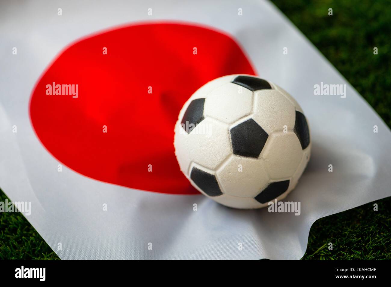 Japanische Fußballnationalmannschaft. Nationalflagge auf grünem Gras und Fußball. Fußball-Wallpaper für Meisterschaft und Turnier im Jahr 2022. Internationale Welt Stockfoto