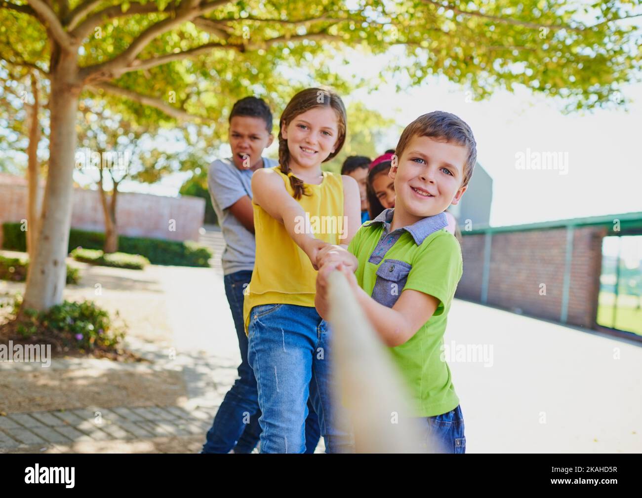 Ziehen Sie härter, wir können das tun. Eine vielfältige Gruppe von Kindern spielen Tauziehen draußen. Stockfoto
