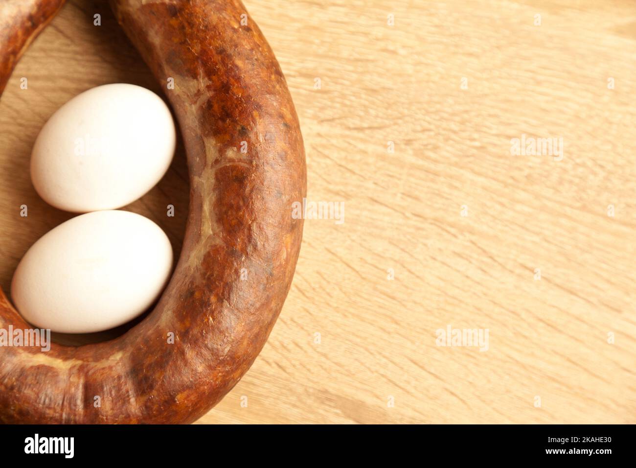 Hausgemachtes kangal-Sucuk aus verschiedenen Gewürzmischungen, die in der türkischen Küche verwendet werden, und zwei weißen Eiern auf Eichenbrettchen Stockfoto