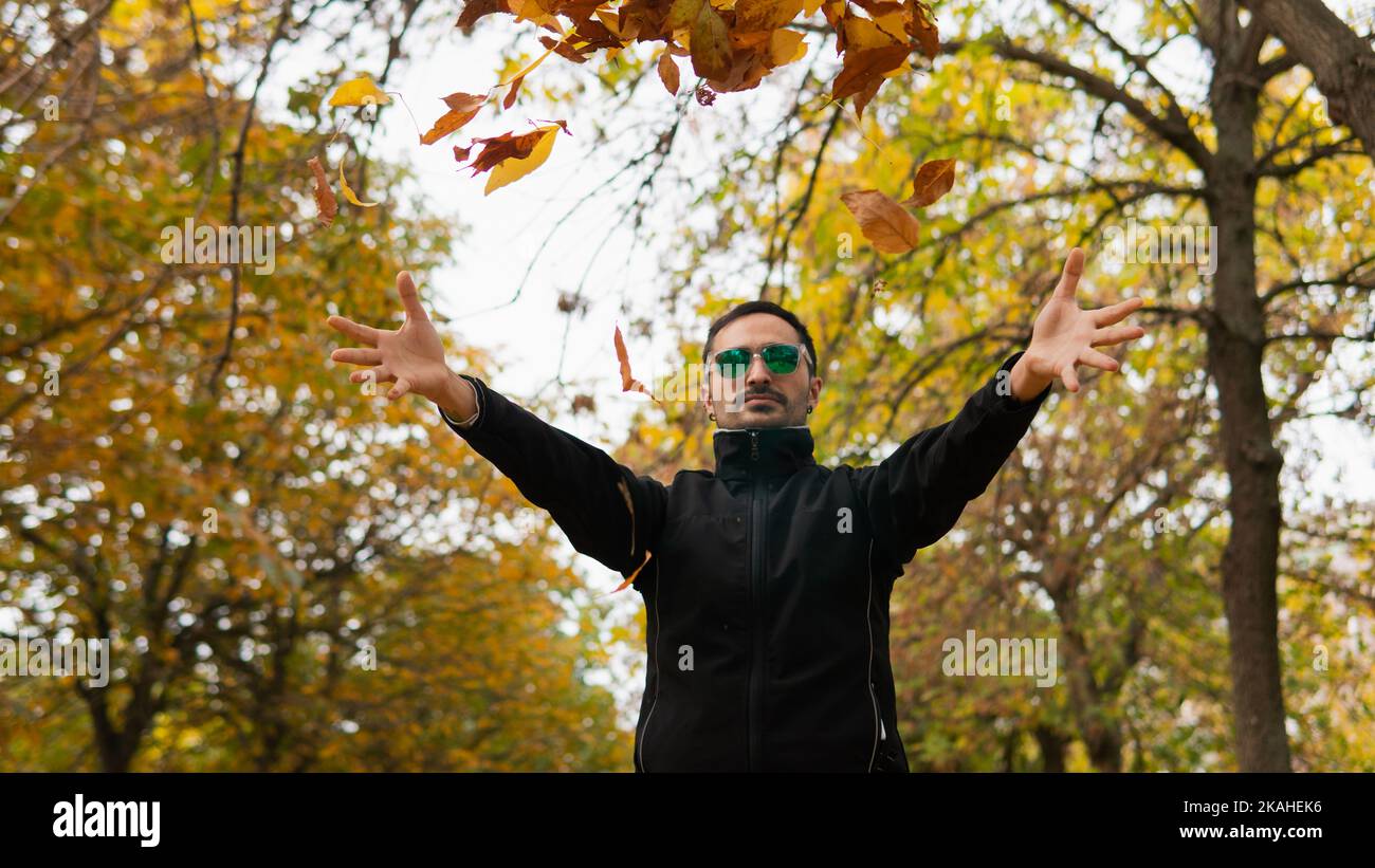 Mann, der im Park steht und Herbstblätter in die Luft wirft, Spanien Stockfoto