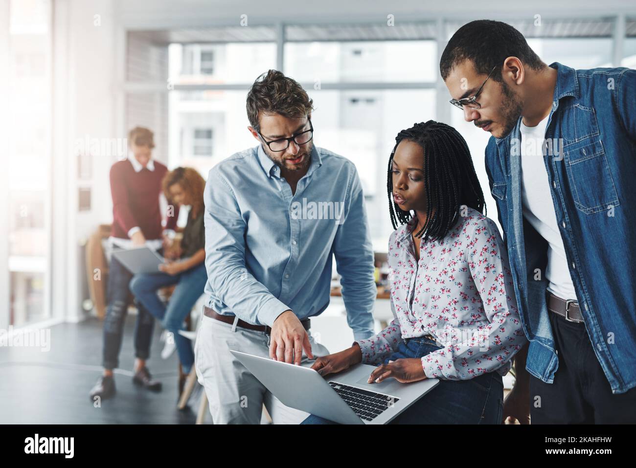 Ein Team braucht es, um ein erfolgreiches Geschäft zu führen. Eine Gruppe von Kollegen, die in einem modernen Büro gemeinsam einen Laptop benutzen. Stockfoto