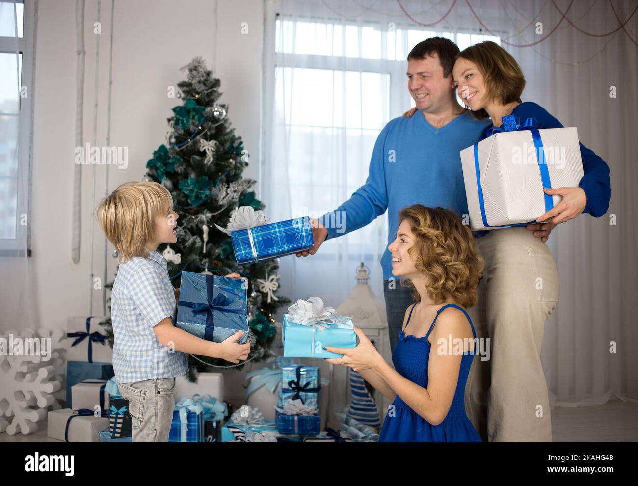 Glückliche Familie, Vater, Mutter, Erwachsene Kinder auf dem Hintergrund der geschmückten Weihnachtsbaum Austausch Geschenke vor Weihnachten. Helle positive Emotionen . festlich a Stockfoto