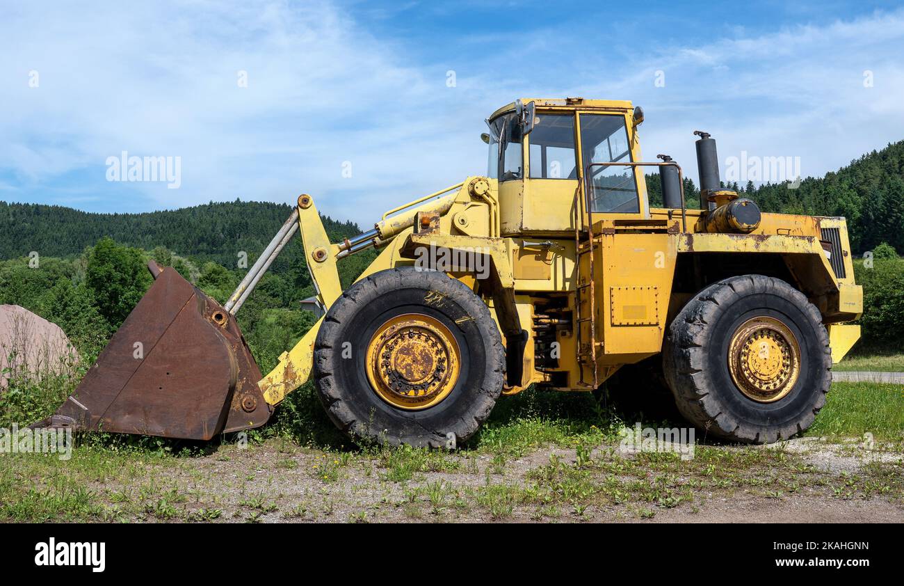 Großer alter gelber Radlader in grüner Landschaft Stockfoto
