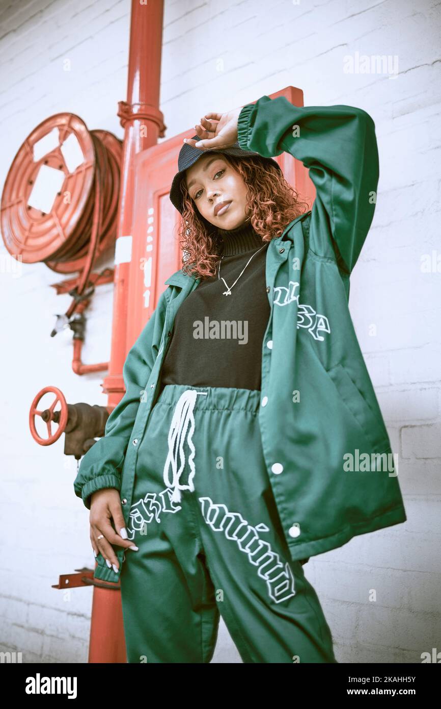 Mode, Wand und schwarze Frau mit grüner Kleidung, modischem Stil oder coolem Hip-Hop-Outfit. Feuer Schlauch, Haltung oder Porträt von Gen z Mädchen mit trendy Stockfoto