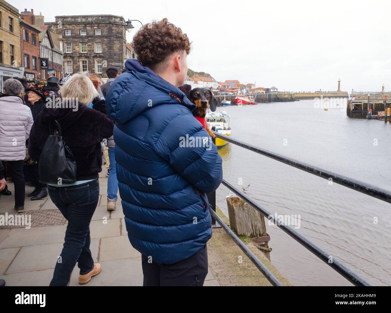 Ein jüngerer Mann mit einem kleinen Hund im Hafen von Whitby Stockfoto