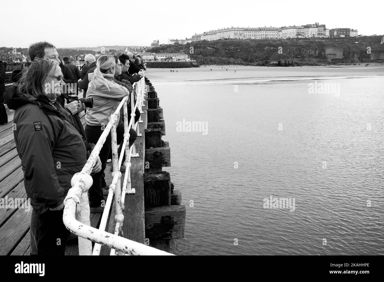Menschen, die über die Bucht von Whitby blicken, in der Hoffnung, Schweinswale zu sehen Stockfoto