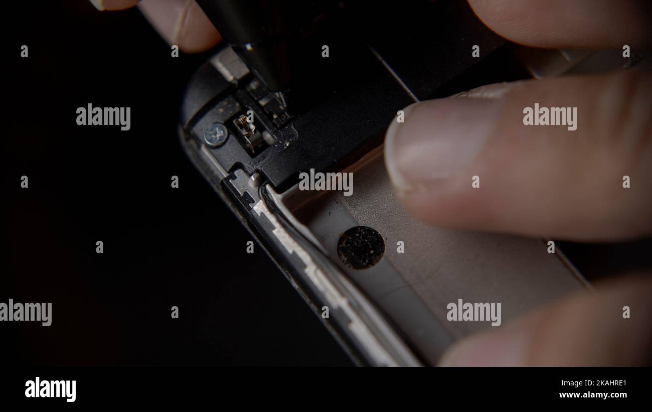 Smartphone-Hersteller oder -Ingenieur untersucht die Rückseite eines Smartphones, extreme Nahaufnahme, Smartphone-Reparatur oder Fertigungskonzept Stockfoto