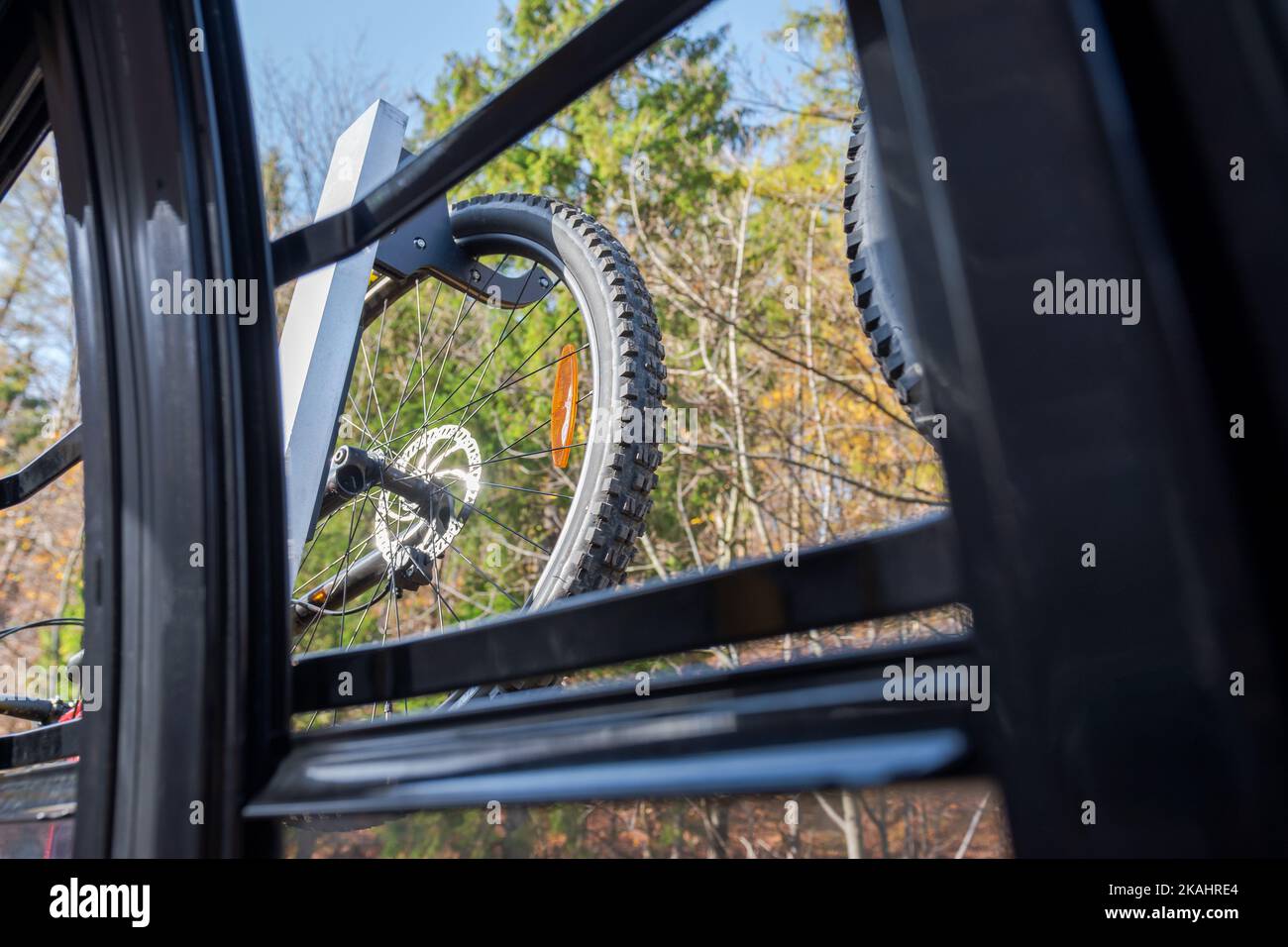 Rad des mtb-Fahrrads, das außerhalb des Wagens einer Bergbahn hängt, gesehen durch das offene Fenster der Gondel. Schöner, herbstlicher, sonniger Tag. Adventur Stockfoto