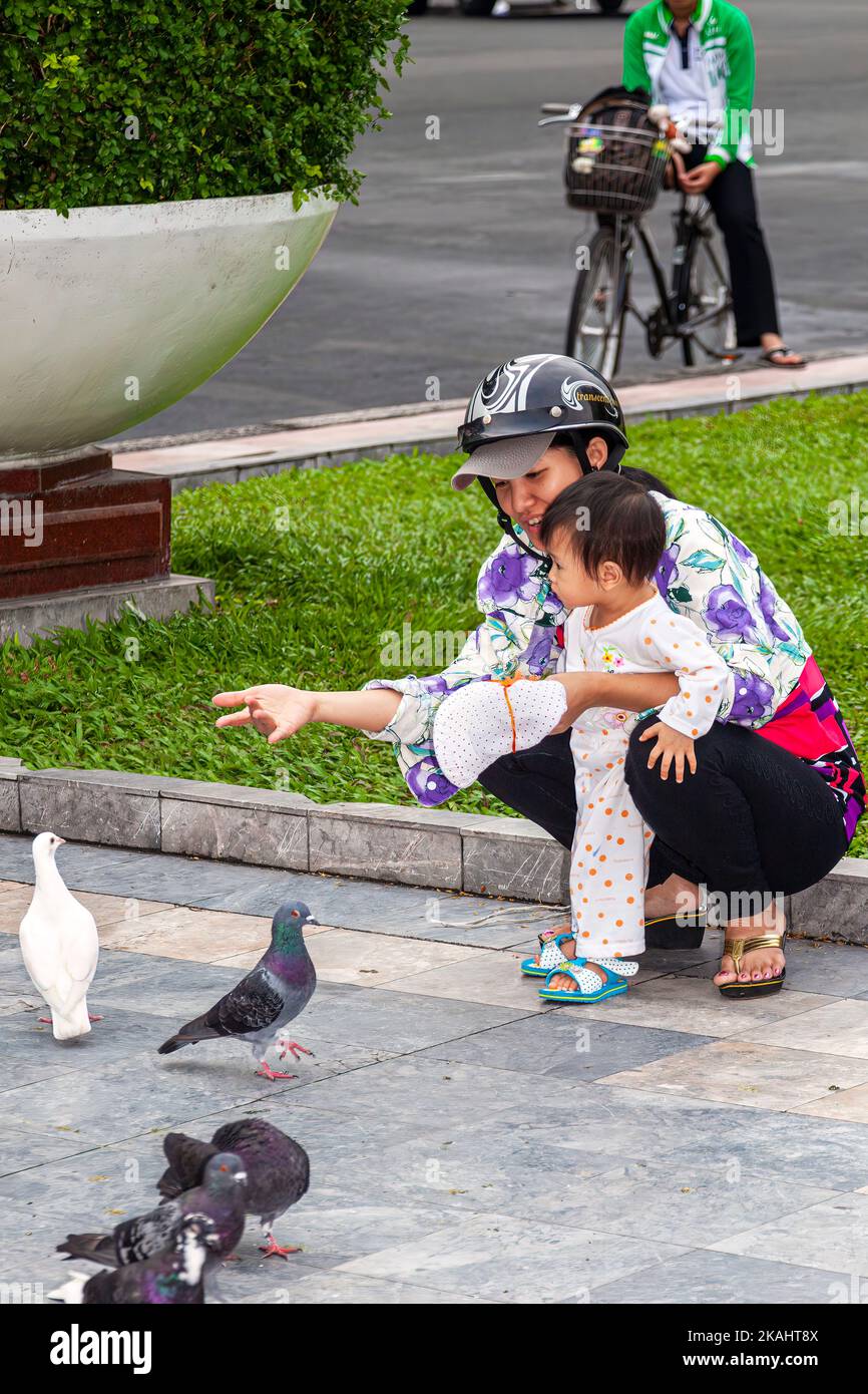 Vietnamesische Mutter und Baby, die Tauben im öffentlichen Park füttern, im Zentrum von Ho Chi Minh, Vietnam Stockfoto