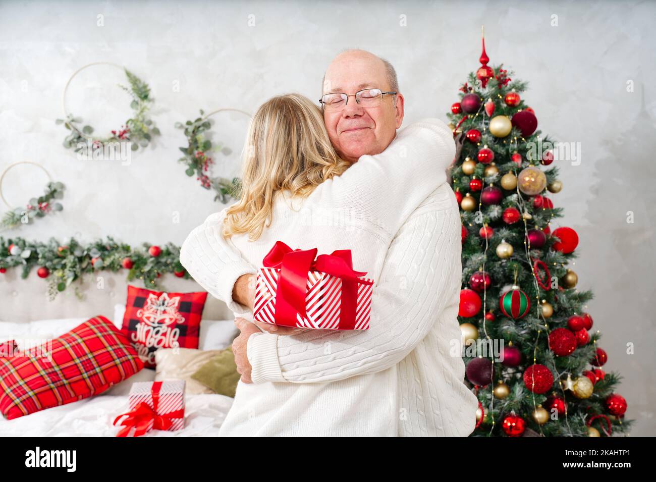 weihnachten, Feiertage und Menschen Konzept - glückliches Paar in santa Hüte Austausch von Geschenken zu Hause. Stockfoto