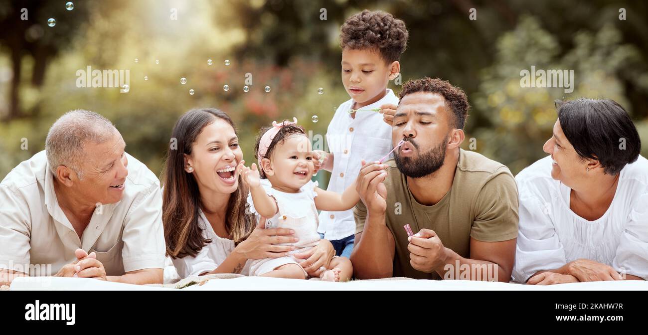 Glücklich, lächelnd und große Familie bläst Blasen in einem Garten auf einem Sommer-Picknick in Puerto Rico. Glück, Großeltern und Eltern mit spielenden Kindern Stockfoto