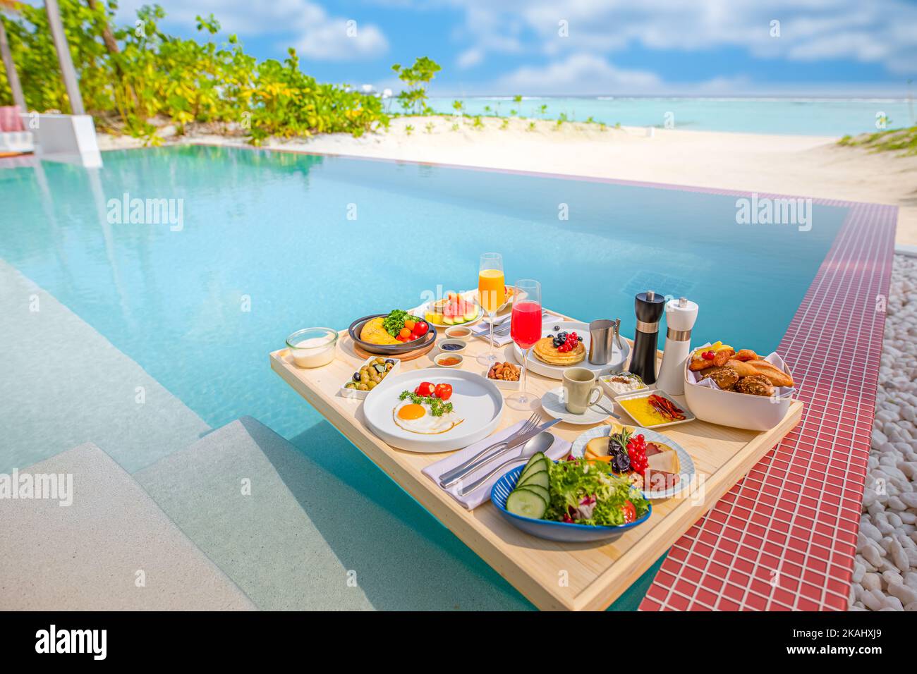 Frühstück im Swimmingpool, schwimmendes Frühstück im luxuriösen tropischen Resort. Tisch relaxen auf ruhigem Poolwasser, gesundes Frühstück und Obstteller Stockfoto