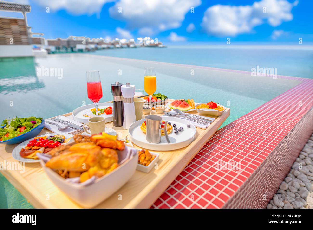 Frühstück im Swimmingpool, schwimmendes Frühstück im luxuriösen tropischen Resort. Tisch relaxen auf ruhigem Poolwasser, gesundes Frühstück und Obstteller Stockfoto