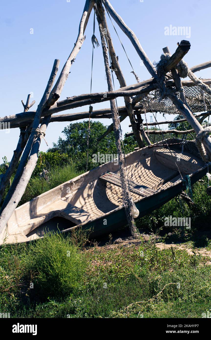 Ein Boot an Land hängt an Baumstämmen. Vertikales Foto. Stockfoto