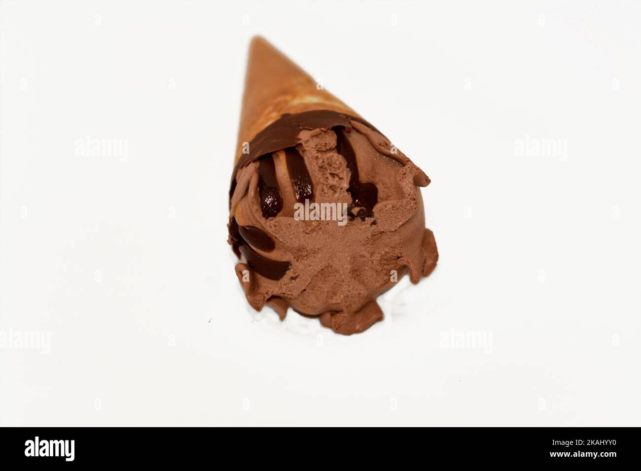 Schokolade-Vanille-Eiscreme-Kugel auf einem Kekskonus mit Schokoladensauce isoliert auf weißem Hintergrund, selektiver Fokus von dunkelbraunem Eiscreme-Kegel mit Stockfoto