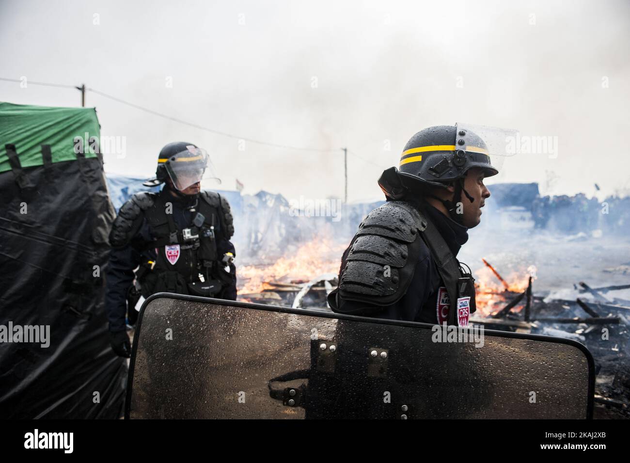 Die Polizei sicherte das Gebiet um das Feuer, nachdem sie lange Minuten auf die Zerstörung des südlichen Teils des Dschungels gewartet hatte. In Calais, Frankreich, am 1. März 2016. Beamte gehen Berichten zufolge Tür-zu-Tür im „Dschungel“-Migrantenlager in Calais, um die Menschen zu überzeugen, den Standort zu verlassen und als Asylbewerber nach Frankreich umgesiedelt zu werden. NGOs und Aktivisten sollen ebenfalls zur Verfügung stehen, um ein gerichtliches Gegenargument zu liefern. Die französischen Abbruchteams begannen Anfang dieser Woche mit dem Abbau von Hütten, aber dies wurde mit Widerstand getroffen, da die Bereitschaftspolizei gezwungen wurde, Tränengas auf Migranten zu feuern, die Steine warfen Stockfoto