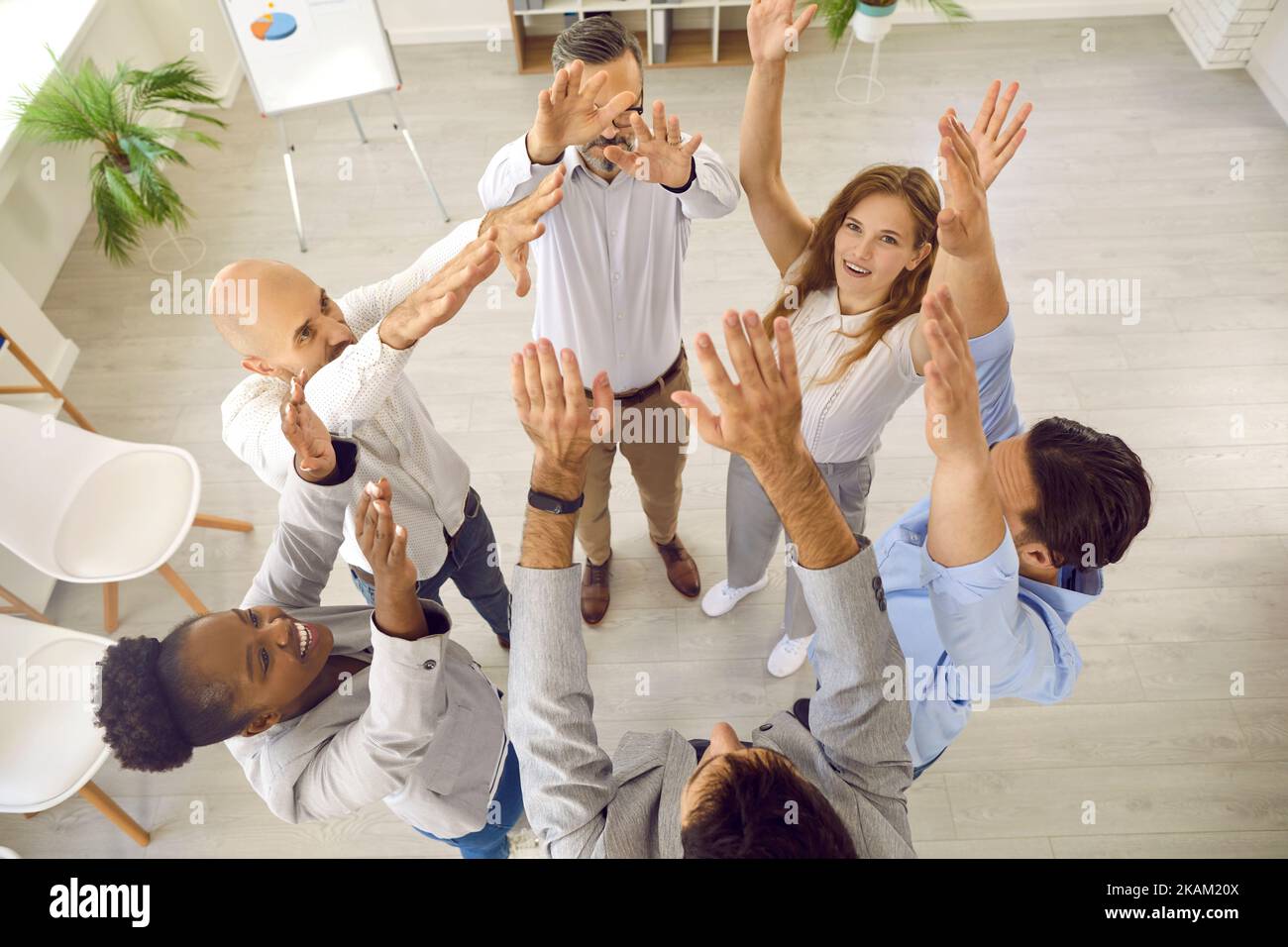 Erfolgreiche Geschäftsleute, die im Teambuilding-Training des Unternehmens tätig sind, stehen mit den Händen im Büro. Stockfoto