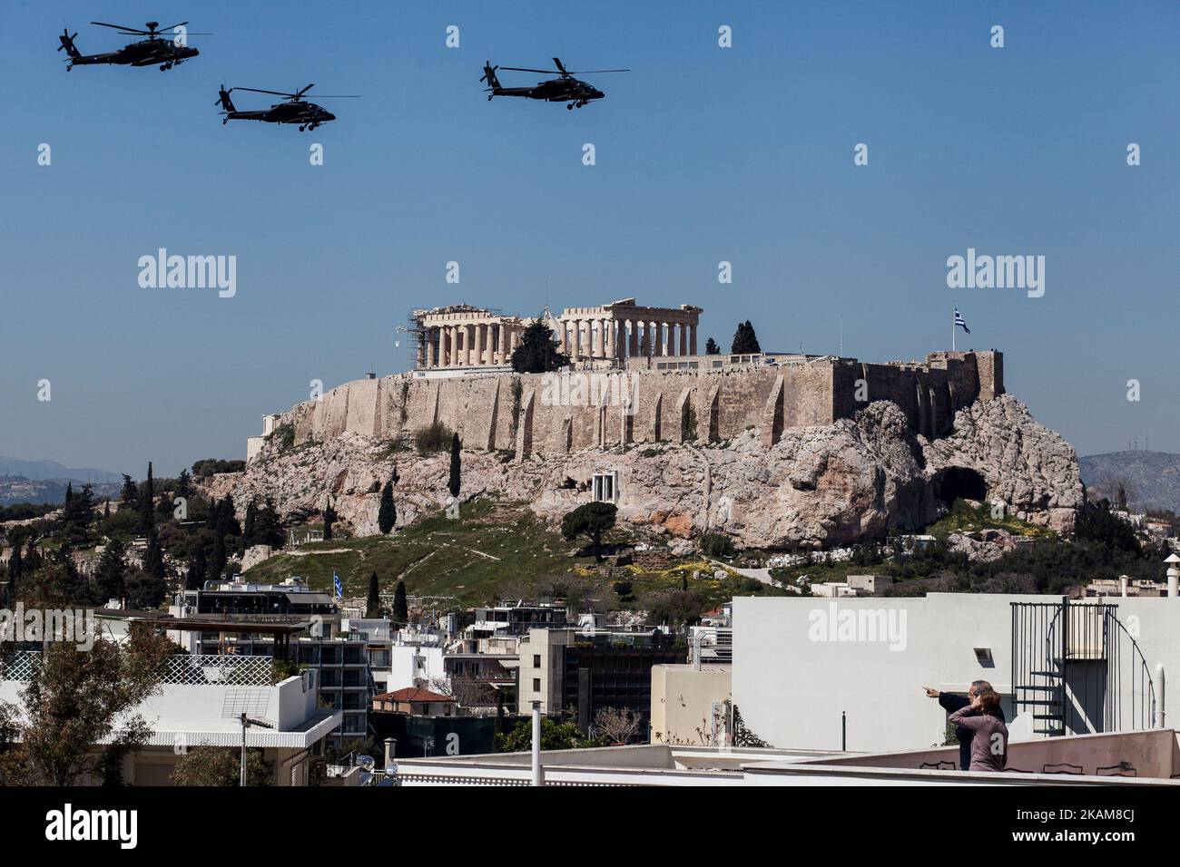 Militärhubschrauber fliegen während der Militärparade zum Gedenken an den Beginn des griechischen Unabhängigkeitskrieges im Jahr 1821 über die Akropolis, während die Menschen von Balkonen und Terrassen aus zusehen. Athen, Den 25. März 2017. (Foto von Kostis Ntantamis/NurPhoto) *** Bitte nutzen Sie die Gutschrift aus dem Kreditfeld *** Stockfoto