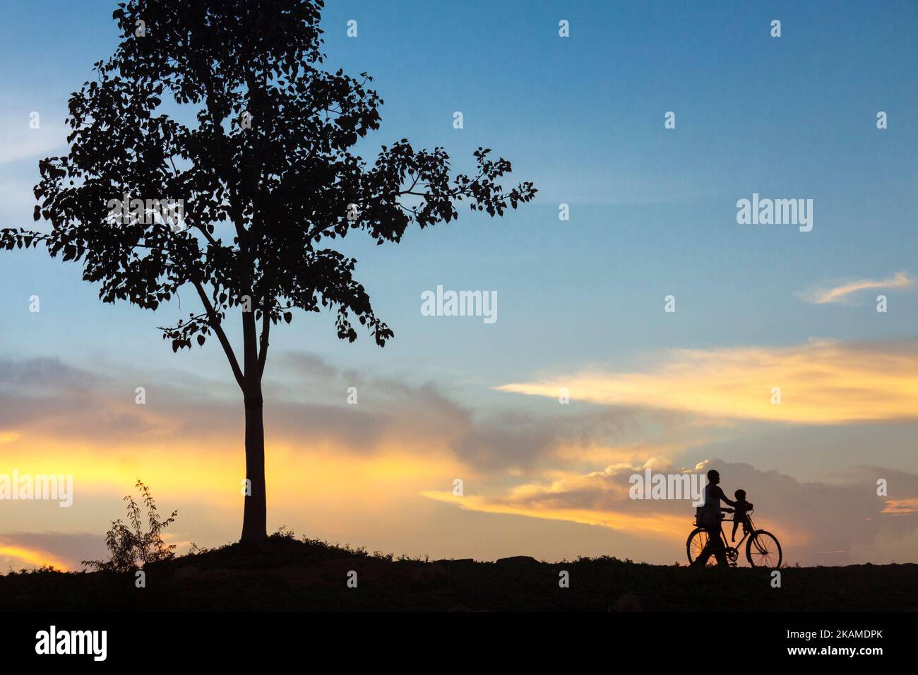 Khajuraho, Madhya Pradesh, Indien: EIN Mann und ein kleines Kind nehmen eine idyllische Fahrradfahrt bei Sonnenuntergang. Stockfoto