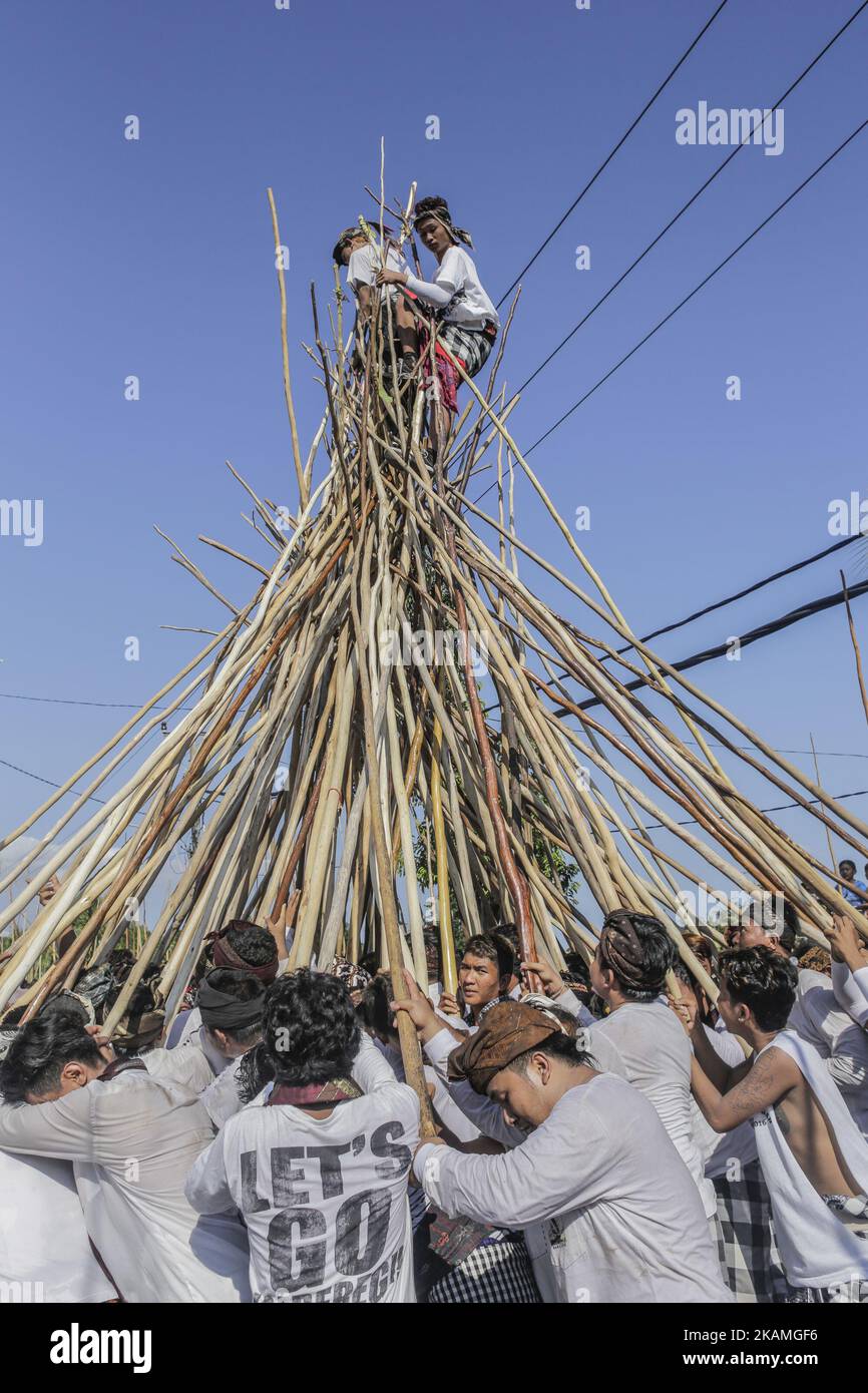 Zwei Männer stehen während des Mekotek-Rituals, das von balinesischen Hindus im Dorf Munggu am 15. April 2017 in Badung, Bali, Indonesien, praktiziert wurde, auf einer hölzernen Pyramide aus Stäben. Das Mekotek-Ritual ist eine traditionelle Zeremonie im Dorf Munggu, bei der der symbolische Sieg des Guten (Dharma) gegen das Böse (Adharma) gefeiert wird, bei dem die Teilnehmer wiederholt auf eine hölzerne Pyramide aus Stäben klettern, wie sie von Zelebranten von einem Tempel zum anderen getragen wird. (Foto von Johanes Christo/NurPhoto) *** Bitte nutzen Sie die Gutschrift aus dem Kreditfeld *** Stockfoto