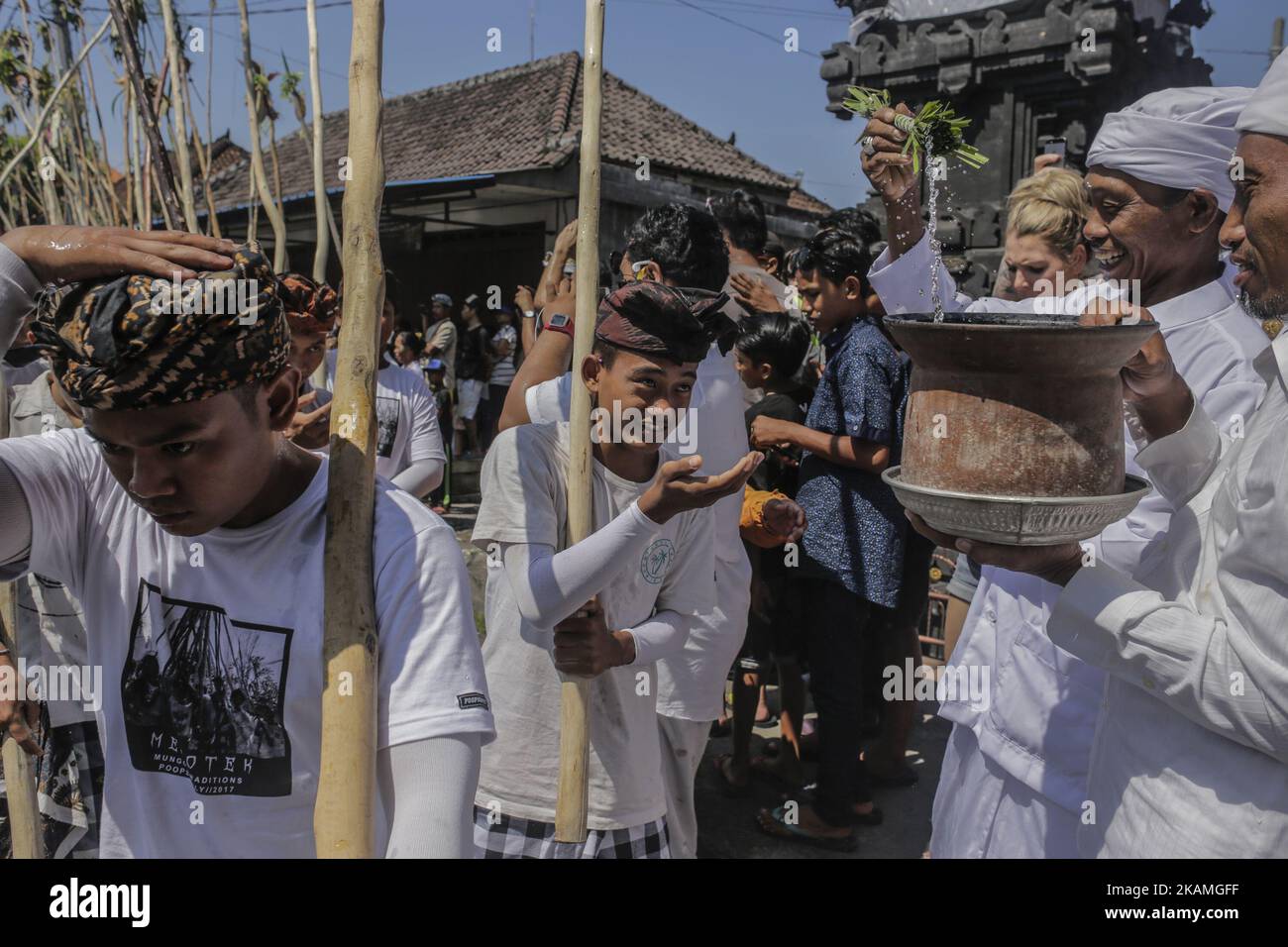 Priester, der jungen Dorfbewohnern Weihwasser gab, bevor das Mekotek-Ritual von balinesischen Hindus im Dorf Munggu am 15. April 2017 in Badung, Bali, Indonesien, praktiziert wurde. Das Mekotek-Ritual ist eine traditionelle Zeremonie im Dorf Munggu, bei der der symbolische Sieg des Guten (Dharma) gegen das Böse (Adharma) gefeiert wird, bei dem die Teilnehmer wiederholt auf eine hölzerne Pyramide aus Stäben klettern, wie sie von Zelebranten von einem Tempel zum anderen getragen wird. (Foto von Johanes Christo/NurPhoto) *** Bitte nutzen Sie die Gutschrift aus dem Kreditfeld *** Stockfoto