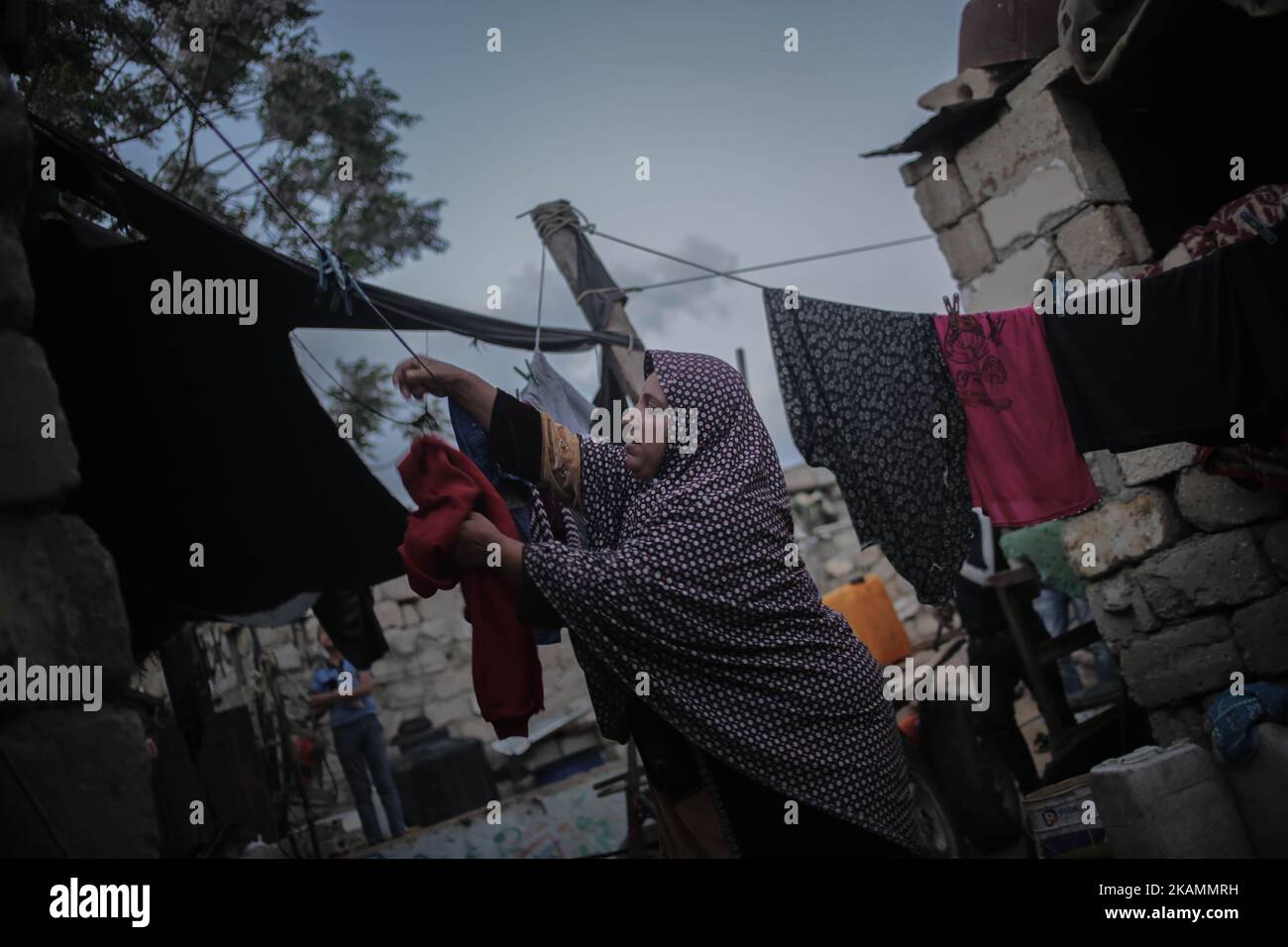 Eine palästinensische Flüchtlingsfrau wäscht sich während eines Stromausfalls im Flüchtlingslager Khanyounis im südlichen Gazastreifen in der Nähe eines Feuers Kleidung, am 23. April 2017. Die meisten Palästinenser im Gazastreifen verwenden Batterien, Generatoren oder Kerzen, um ihre Häuser anzuzünden. Die Bewohner von Gaza, wo rund 1,8 Millionen Menschen leben, erleben täglich rund 20 Stromausfälle. Berichten zufolge ging der einzige funktionierende Strom im Gazastreifen am 16. April 2017 aus dem Treibstoff und hörte auf zu arbeiten. Der Betrieb des Werks der Gaza Power Generating Company funktioniert in der Regel nur acht Stunden am Tag, nachdem der Brennstoff durch den israelischen Ker in den Gazastreifen eingedringen ist Stockfoto