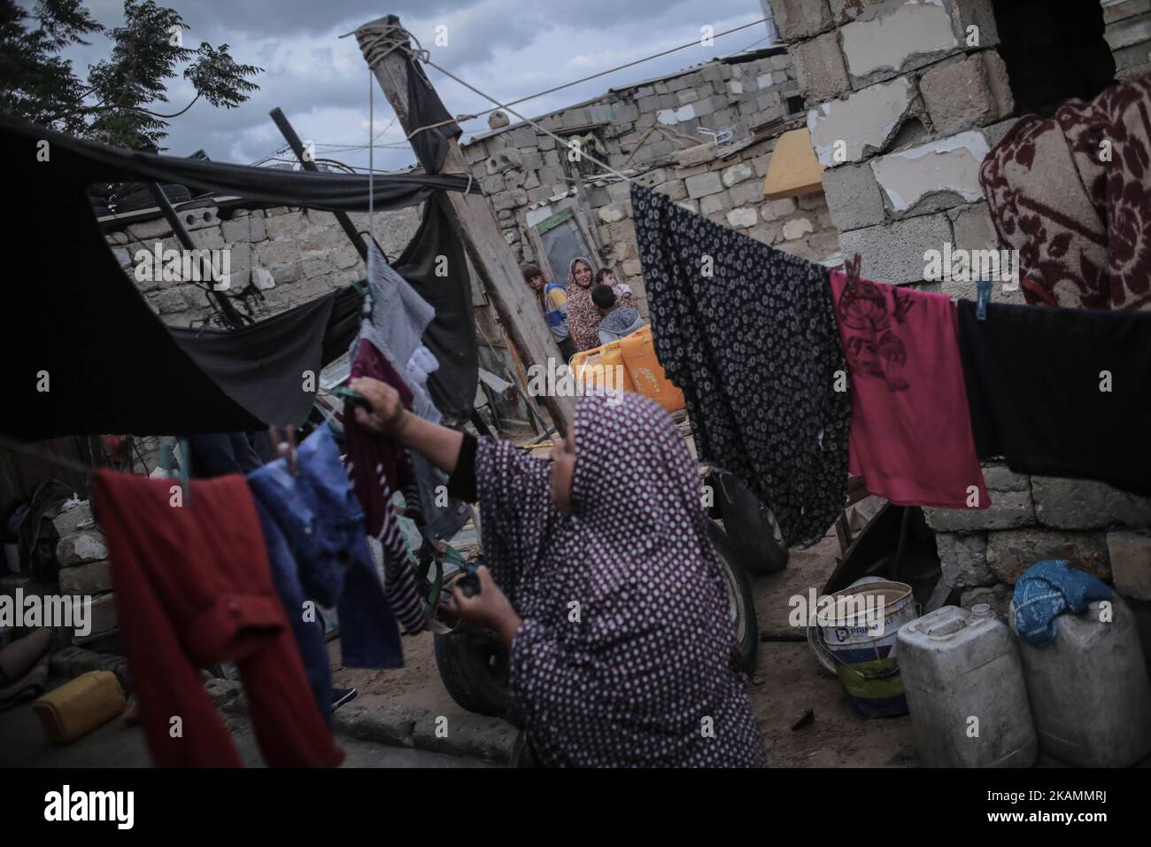 Eine palästinensische Flüchtlingsfrau wäscht sich während eines Stromausfalls im Flüchtlingslager Khanyounis im südlichen Gazastreifen in der Nähe eines Feuers Kleidung, am 23. April 2017. Die meisten Palästinenser im Gazastreifen verwenden Batterien, Generatoren oder Kerzen, um ihre Häuser anzuzünden. Die Bewohner von Gaza, wo rund 1,8 Millionen Menschen leben, erleben täglich rund 20 Stromausfälle. Berichten zufolge ging der einzige funktionierende Strom im Gazastreifen am 16. April 2017 aus dem Treibstoff und hörte auf zu arbeiten. Der Betrieb des Werks der Gaza Power Generating Company funktioniert in der Regel nur acht Stunden am Tag, nachdem der Brennstoff durch den israelischen Ker in den Gazastreifen eingedringen ist Stockfoto