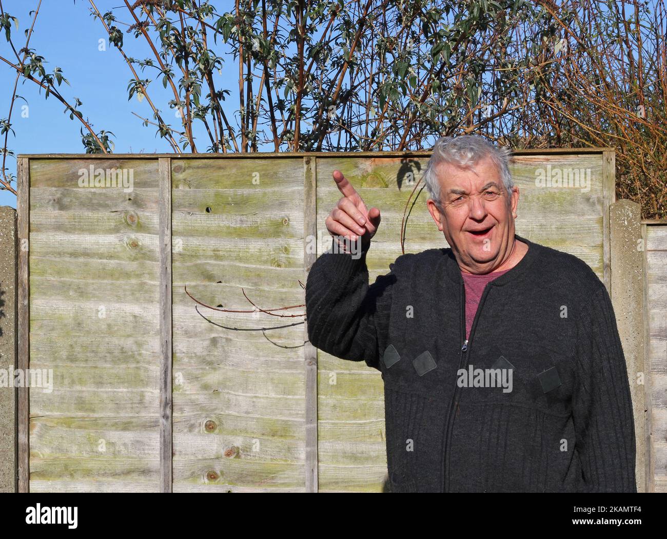 Älterer Mann, der auf die Kamera blickt und entweder nach links oder rechts zeigt. Den Weg weisen. Stockfoto