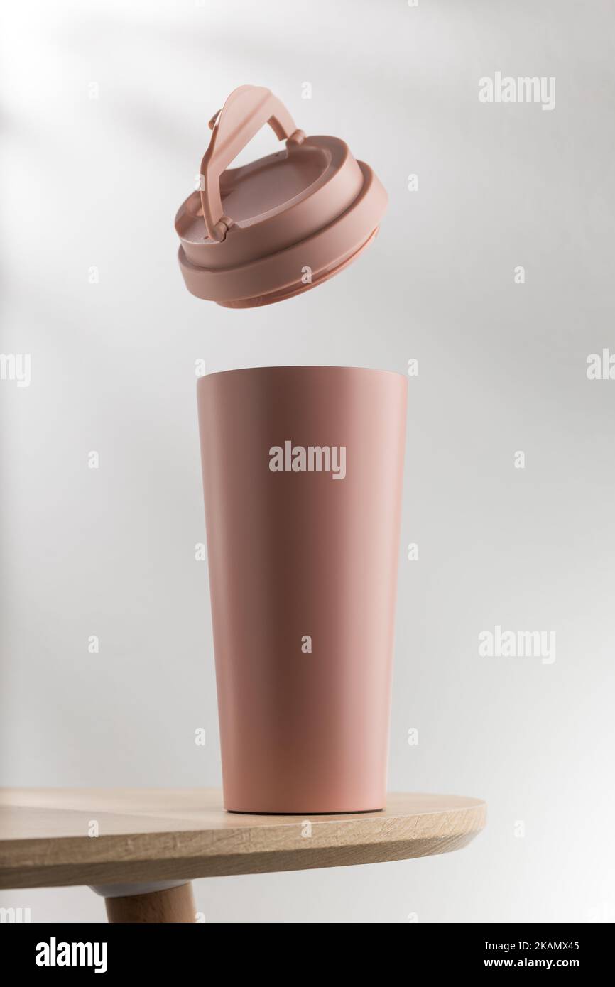 Rosafarbener Becher oder Thermos auf Holztisch Stockfoto