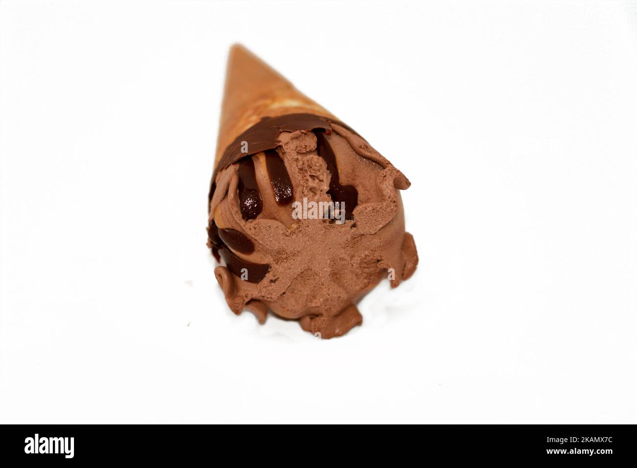 Schokolade-Vanille-Eiscreme-Kugel auf einem Kekskonus mit Schokoladensauce isoliert auf weißem Hintergrund, selektiver Fokus von dunkelbraunem Eiscreme-Kegel mit Stockfoto
