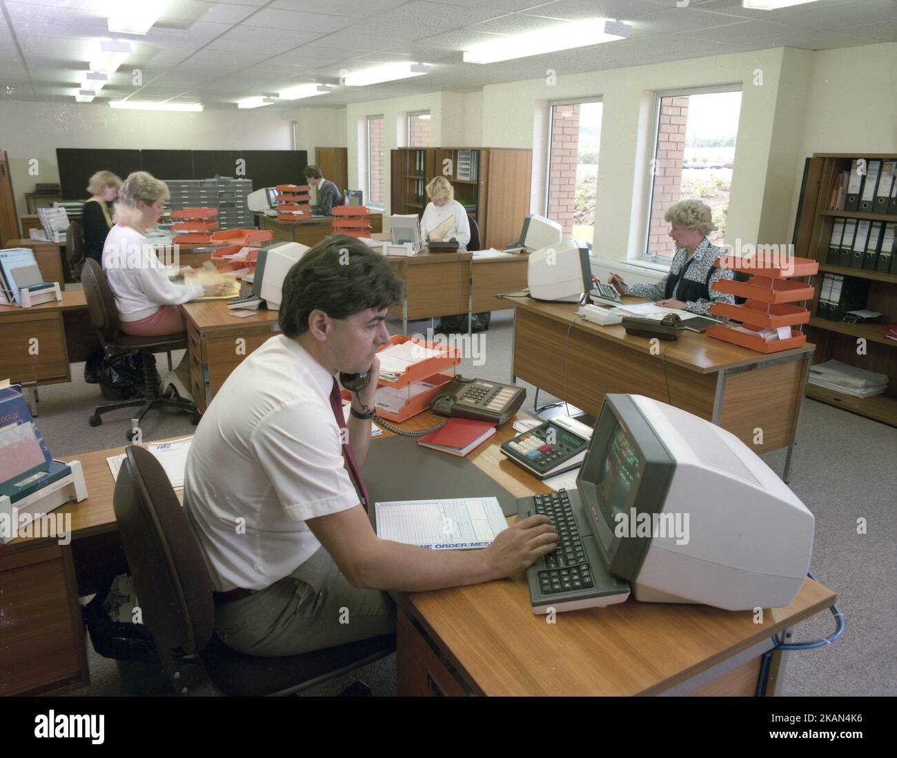 1989, historische Großraumbüros, Angestellte an Schreibtischen, einige am Telefon, England, Großbritannien mit Computerkonsolen oder PCs der damaligen Zeit. Anfang 80s, als IBM seinen PC auf den Markt brachte, begann der Markt für kleine Desktop-PCs. Stockfoto